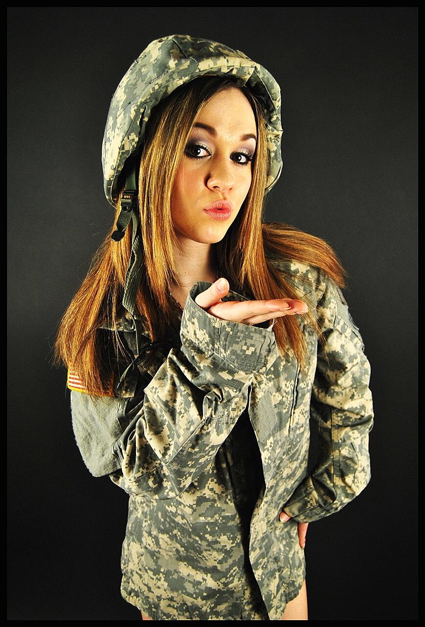 Military beauty exposes her slim figure and poses in black high heels